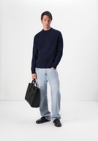 Tengerész navy crew-neck pulóver, világoskék laza farmerek, fekete loaferek és egy fekete bőr táska. Egyszerű dizájn, strukturált kötött anyaggal.