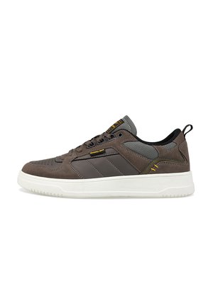 Baskets marron avec une tige en daim et en maille, dotées de trois bandes ton sur ton, d'une semelle blanche et d'accents jaunes sur le talon et la languette.