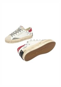 Sneaker bianche con accenti rossi e neri, punta in suede, suola testurizzata, dettagli decorativi in argento e branding sulla linguetta e sul tallone.