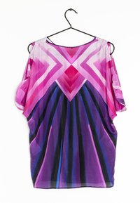 Top trasparente e multicolore con un motivo a zigzag viola, rosa e blu. Vestibilità ampia con maniche corte, che scende fino all'altezza dei fianchi.