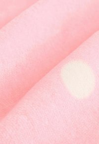 Rózsaszín bolyhos anyag, puha, plüss textúrával, körkörös fehér mintával. A felülete simának és enyhén fénylőnek tűnik.