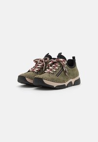 Chaussures en daim vert olive avec des accents noirs, dotées de lacets fantaisie et d'une fermeture éclair sur le côté. Semelle épaisse en caoutchouc noir pour une adhérence et un confort optimal.