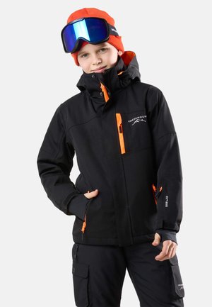 Schwarze Skijacke mit orangefarbenen Akzenten, wasserfesten Reißverschlüssen, verstellbarer Kapuze und einem weichen Innenfutter. Kombiniert mit schwarzen Cargo-Hosen.
