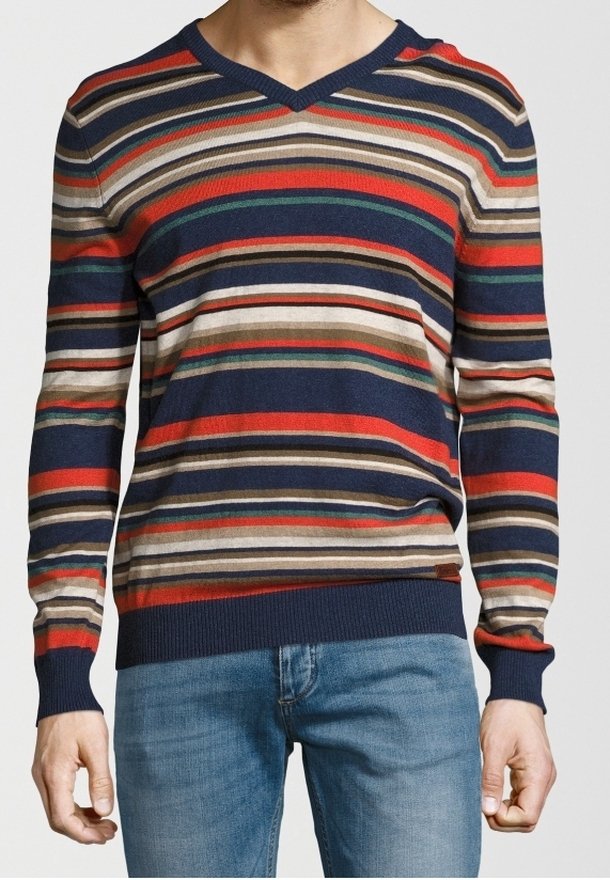 Homme portant un pull ajusté à col en V avec des rayures horizontales bleu marine, rouge, beige, vert et orange, associé à un jean bleu clair.