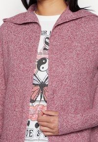 Gebreid vest in een gemêleerde bordeauxrode kleur met een kraag, open voorkant en lange mouwen. Gekenmerkt door een zachte, gestructureerde stof.