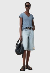 Lys blå bomulds V-hals T-shirt, slidte lyse denim Bermuda shorts, sort bredt bælte, oversized sort læder håndtaske, sorte sandaler med guld accenter.