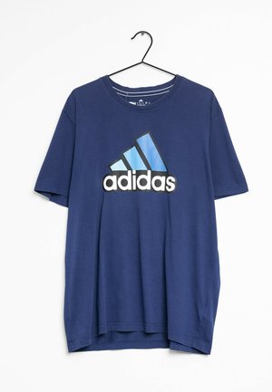 Granatowy t-shirt Adidas z dużym niebiesko-białym logo Adidas na środku klatki piersiowej, wiszący na czarnym wieszaku na białym tle.