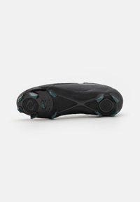 Semelle de chaussure de sport noire avec une surface en caoutchouc texturé, des crampons distincts pour l'adhérence, et un design épuré avec des accents teal.