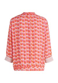 Blouse ample à manches longues avec motif géométrique de feuilles orange, rose et blanc et larges poignets blancs à rayures roses, vue de dos.