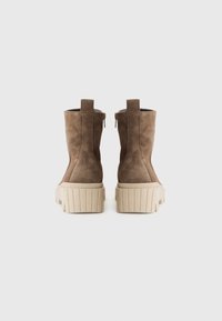 Bruine suède enkellaarsjes met een platformzool, voorzien van een gestructureerde beige buitenzool en kleine achterste lipjes voor gemakkelijk aan- en uittrekken.