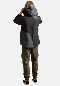 Zwarte en grijze hooded jack met een gestructureerde stof, met een losse pasvorm en een bicolore ontwerp, gecombineerd met olijfgroene cargo pants en zwarte sneakers.