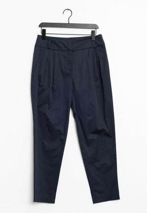 Pantalon bleu marine fuselé avec plis et poches latérales, suspendu sur un cintre en plastique noir devant un fond blanc.