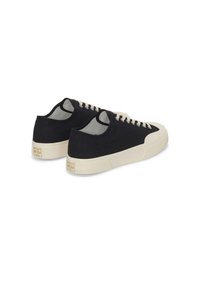 Svarta canvas sneakers med en beige gummisula, rund tå och kontrasterande snören. Minimalistisk design med slät textur.