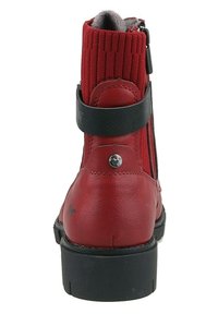 Bottine en cuir rouge avec tige textile côtelée, accent de sangle noire et fermeture éclair sur le côté. Elle dispose d'une semelle en caoutchouc noir robuste.