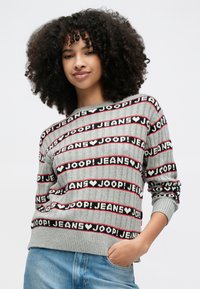 Γκρι πλεκτό πουλόβερ με έντονες μαύρες και κόκκινες ρίγες και επαναλαμβανόμενο κείμενο "JOOP! JEANS". Ριμπ υφή και μανίκια με χαλαρή εφαρμογή.