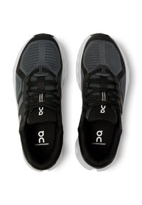 Baskets de course noires et grises avec des panneaux en mesh, un bout arrondi et une semelle rembourrée. Présente un logo contrasté et un design minimaliste.