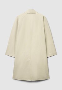 Beiger kniehoher Mantel mit geradem Schnitt, weiten Ärmeln und einem Rückenschlitz. Glatte Textur mit klassischem Kragen.