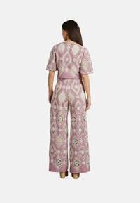 Zweiteiliges Outfit bestehend aus einem kurzen Oberteil und einer weiten Hose, gefertigt aus hellrosa Stoff mit kontrastierenden weißen Blumen- und Diamantmustern.