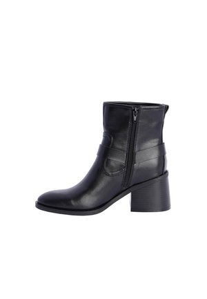 Botas negras de tobillo de cuero suave, con cremallera lateral, borde superior curvado y tacón apilado. Acentuadas con una correa horizontal.