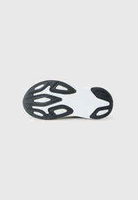 White shoe sole with black rubber tread patterns laid flat against a plain, light background.