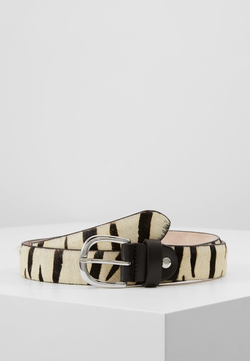 Ceinture enroulée avec imprimé zèbre noir et blanc, boucle métallique argentée et boucle en cuir noir, présentée sur une surface blanche.