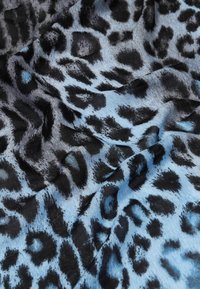 Tessuto azzurro chiaro con un motivo a stampa leopardo nera. La texture appare liscia con una leggera lucentezza.