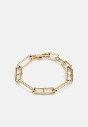 Bracelet ton or avec maillons rectangulaires et ovales allongés, finition polie et fermeture à boucle sur fond blanc.
