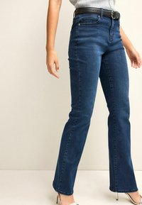 Blue denim flared jeans with a high waist, slight stretch, five pockets, and a black belt featuring a silver buckle. Smooth texture.