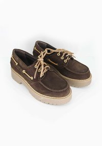 Scarpe in suede marrone con lacci beige, dotate di occhielli dorati e di una suola spessa e testurizzata beige. Design classico da barca con dettagli di cucitura.