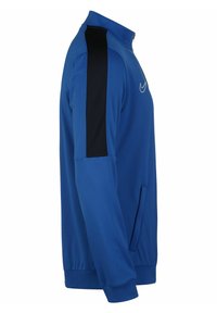 Blaue Sportjacke mit Reißverschlusskragen, schwarzen Seitenpaneelen und einem Logo auf der Brust. Mit Taschen und einem glatten, leichten Material.