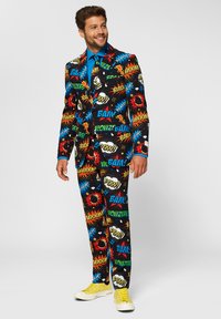 Colorful suit with comic-style graphics including words like "BAM!" and "WOWZERS." Made of smooth fabric; paired with a blue shirt and yellow sneakers.