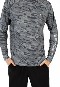 Maglia atletica a maniche lunghe in grigio con un motivo di camouflage geometrico. Presenta un collo rotondo e il logo "SPYDER" in bianco sulla manica sinistra.