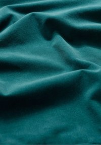 Tissu côtelé bleu sarcelle à la texture douce, présentant des plis et froissements légers, avec une surface lisse et uniforme, idéale pour le rembourrage ou les vêtements.