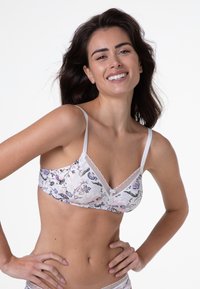 Bralette con motivo floreale in tessuto morbido, caratterizzato da una scollatura a V, spalline bianche e rifiniture in pizzo. I colori chiari dominano il design.