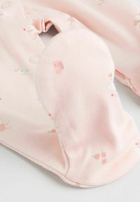 Lyserød babytøj i blødt stof med blomstermønster og trykknapper til lukning. Har en model med futter og afrundede tæer.