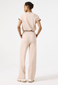 Top de punto beige con mangas cortas y pantalones de cintura elástica, ambos con un corte relajado y textura suave, combinados con zapatos de suela gruesa.