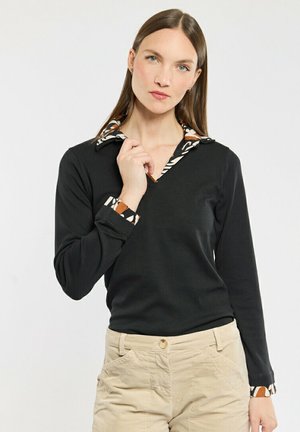 Haut noir à manches longues avec un col en V, doté d'un col et de poignets à motifs dans des tons terre. Texture lisse, coupe décontractée et design minimaliste.