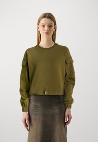 Sudadera verde oliva con mangas raglán, tejido texturizado, diseño corto, puños elásticos y un cordón ajustable en el dobladillo.