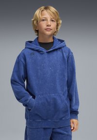 Felpa con cappuccio blu dalla finitura testurizzata, con tasca frontale e polsini a coste. Dettaglio del logo nero sul petto.