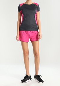 Conjunto de ropa deportiva que consiste en una camiseta atlética de manga corta negra y rosa, combinada con pantalones cortos rosas y zapatillas de correr negras. Tejido suave, diseño ajustado.
