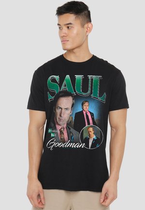 Schwarzes Baumwoll-T-Shirt mit grafischen Drucken eines Charakters, versehen mit dem Text "SAUL Goodman" und "Breaking Bad" in verschiedenen Farben.
