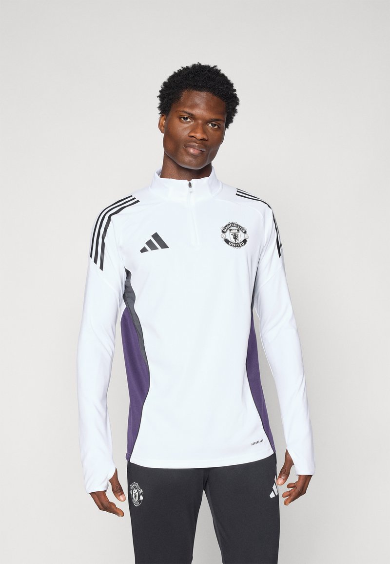 Hvit atletisk kvart-zip skjorte med svarte og lilla sidepaneler, med tre svarte striper på skuldrene og en Manchester United-logo.
