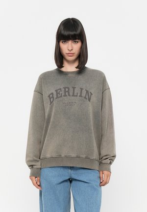 Grauer, kurzkreditierter Sweatshirt mit "BERLIN" in dunkelbraun bedruckt, mit gerippten Bündchen, runder Halslinie und einem verwaschenen Look.