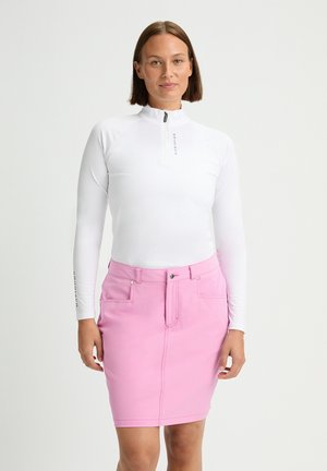 Maglia bianca con zip e maniche lunghe, colletto alto, abbinata a una gonna di colore rosa chiaro, lunghezza ginocchio, con tasche frontali e zip frontale.