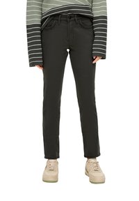 Jeans gris foncé avec une coupe slim et un design à cinq poches, assortis à un pull rayé vert et noir et des baskets beiges.