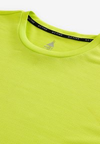 Limegrøn atletisk t-shirt med rund halsudskæring, lavet af mesh-stof med en struktureret overflade, og en sort krave med 'ACTIVE' mærkning.