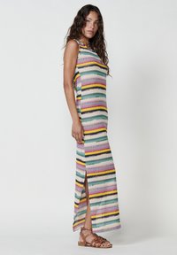 Gestreiftes Maxikleid mit horizontalen Linien in Pastellfarben, seitlichem Schlitz und ärmellosem Design. Das Material wirkt texturiert und leicht.