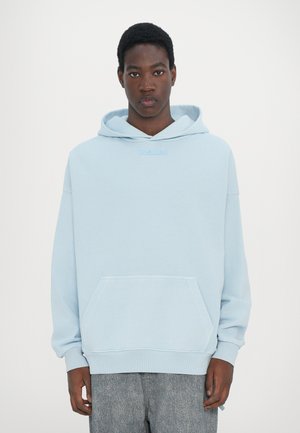 Light blue hoodie with a kangaroo pocket, soft fabric texture, ribbed cuffs and hem, featuring a subtle logo on the chest.