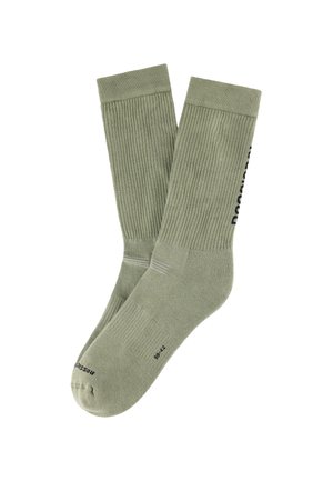 Paar olivgrüner Knöchelsocken mit geripptem Muster und schwarzem Text an den Seiten, flach auf einem weißen Hintergrund dargestellt.