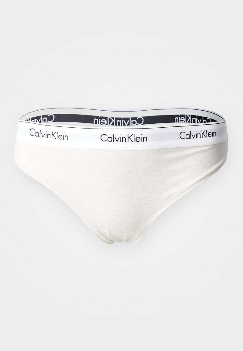 Hvite bomullsbikini-truser med en svart og hvit merkeband med "Calvin Klein"-logo. Myk og glatt tekstur.